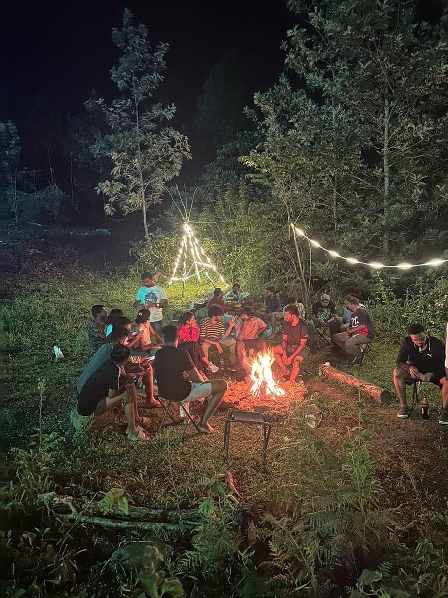 The group gathered around the campfire under string lights